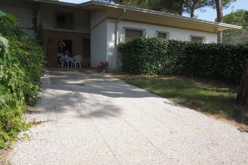 une maison blanche avec un trottoir devant elle dans l'établissement Villa Continenti, à Lignano Sabbiadoro