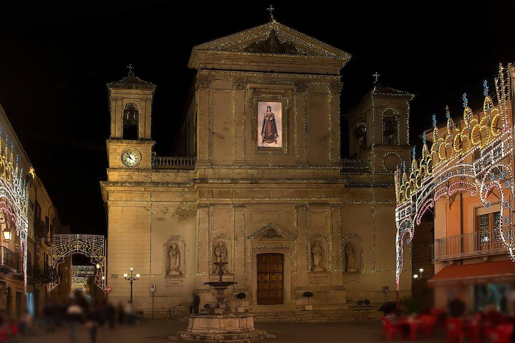 Pratola PelignaにあるAppartamento Il Corsoの時計塔とクリスマス灯のある古い建物