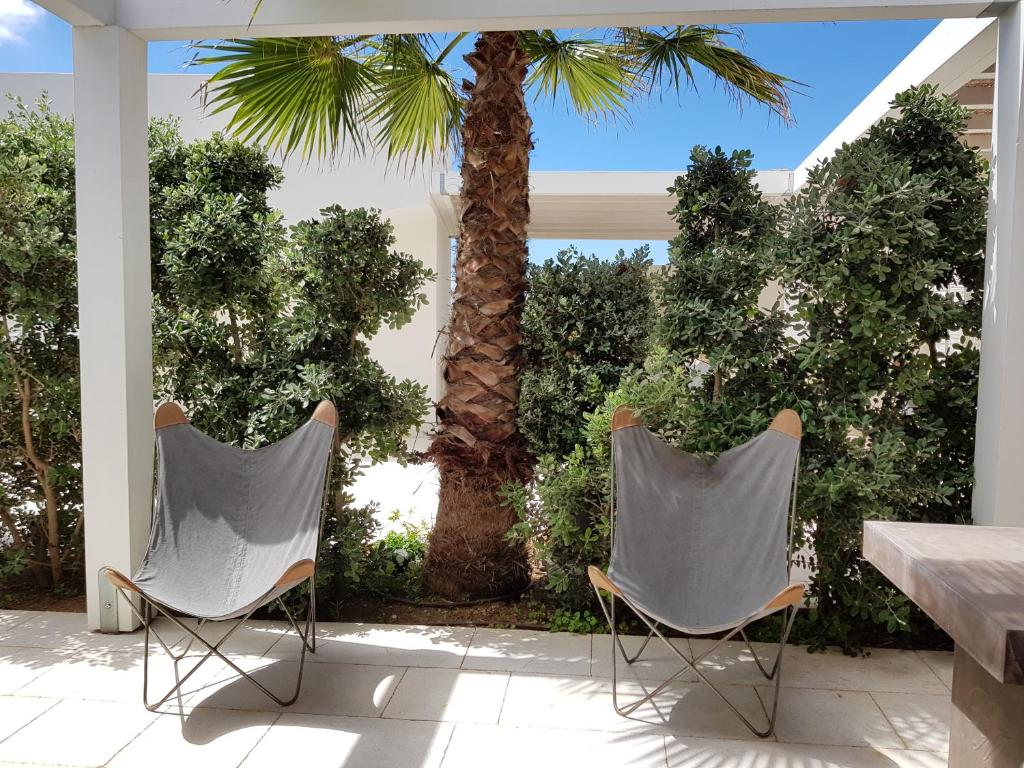 two chairs sitting on a patio with a palm tree at Casa Mirella in Favignana