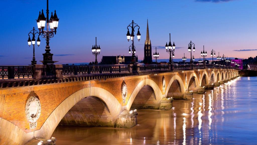 a bridge over the water with lights on at Chambres Élégance - Parc Bordelais in Bordeaux