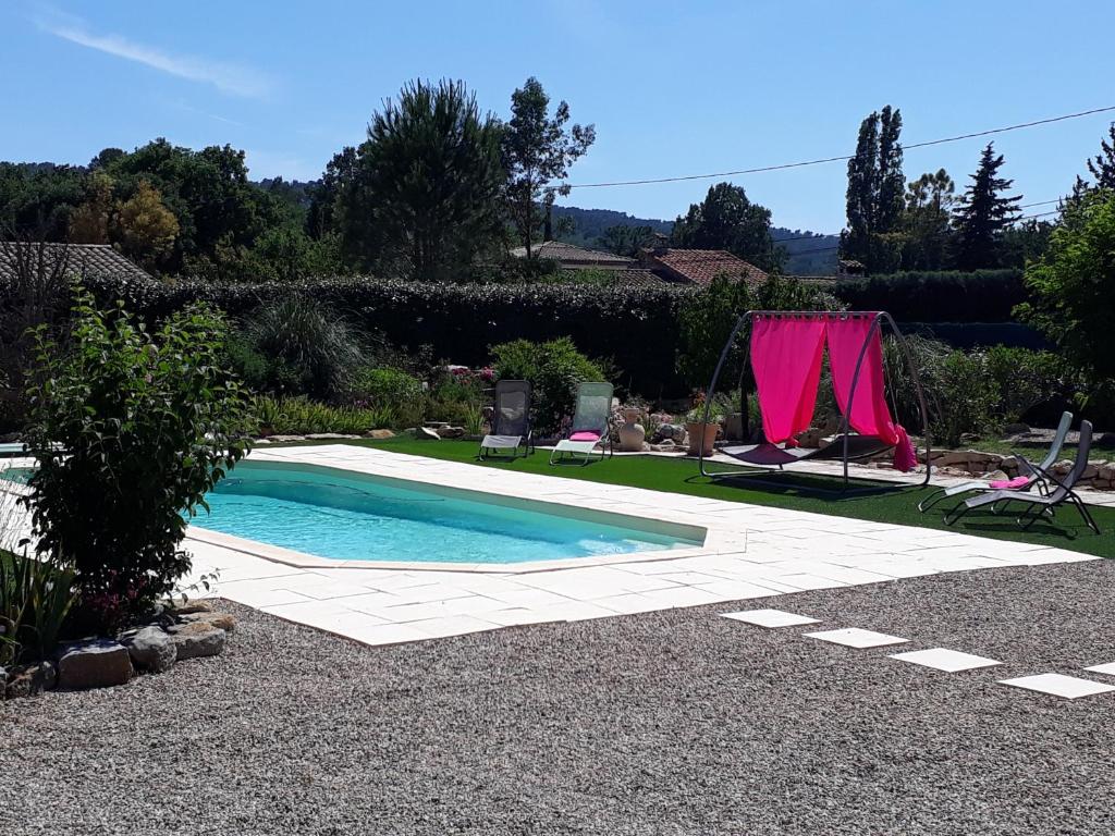 una piscina en un jardín con una cortina rosa en La Colombe, en Tourrettes