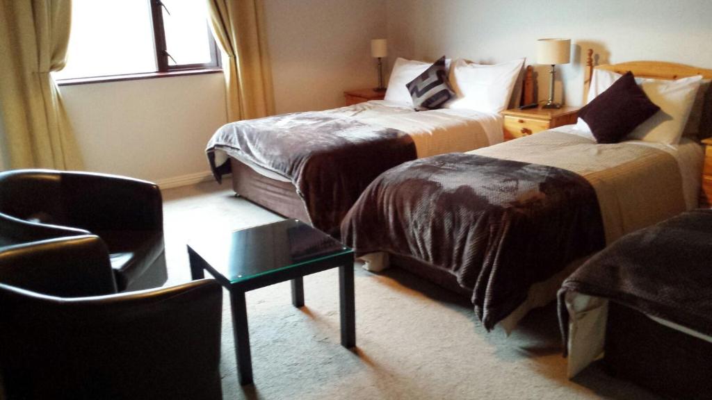 a hotel room with two beds and a chair at Ben Breen House B&B in Clifden