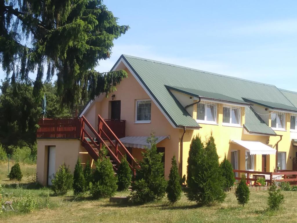 een geel huis met een groen dak bij Agroturystyka Zielona Polana in Wąglikowice