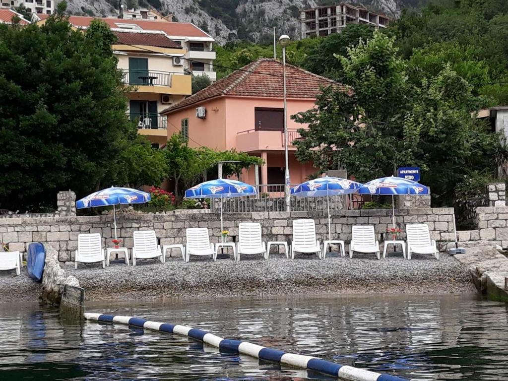 a group of chairs and umbrellas next to the water at Apartments Vido in Kotor