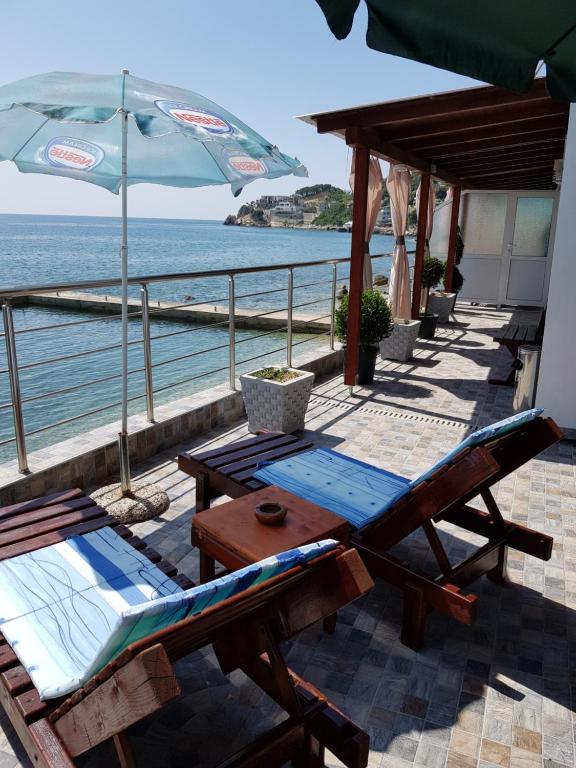 une terrasse avec une table, des chaises et un parasol dans l'établissement Holiday House Kruce, à Ulcinj