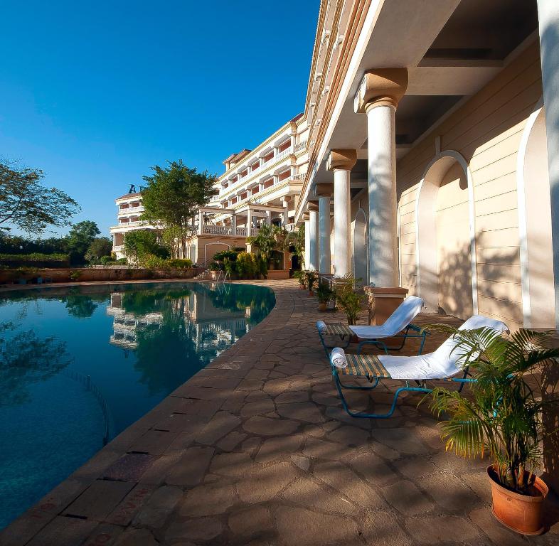 a hotel with a swimming pool and two lounge chairs at The Lagoona Resort in Lonavala