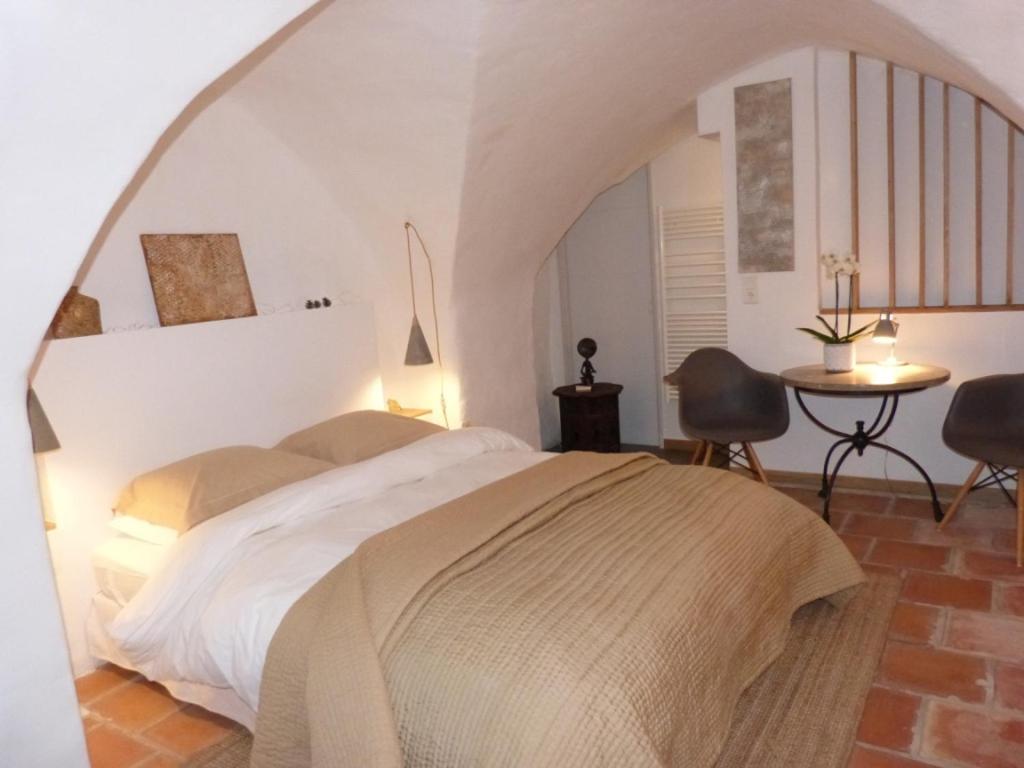 een slaapkamer met een bed en een tafel en stoelen bij le tilleul in Villevieille