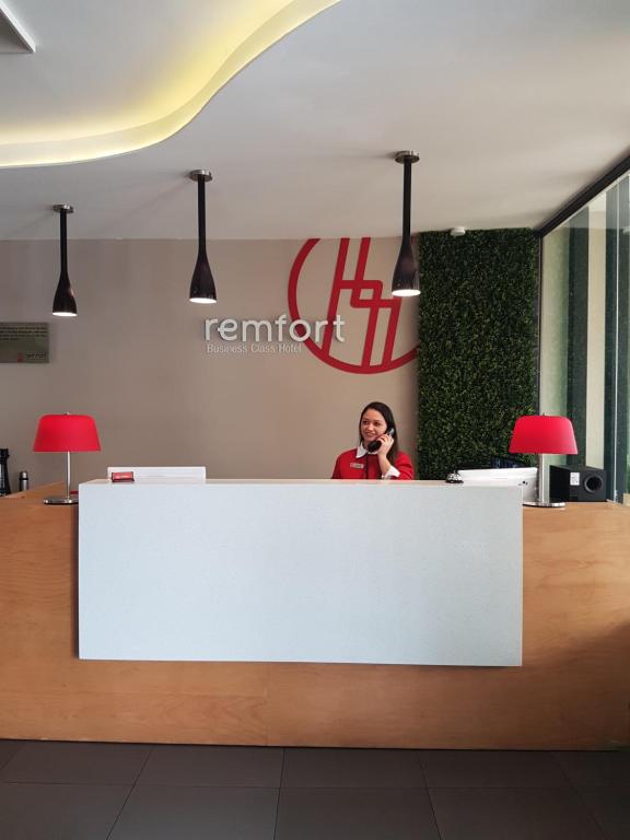 a woman talking on a cell phone behind a counter at Remfort Hotel in Santa Ana