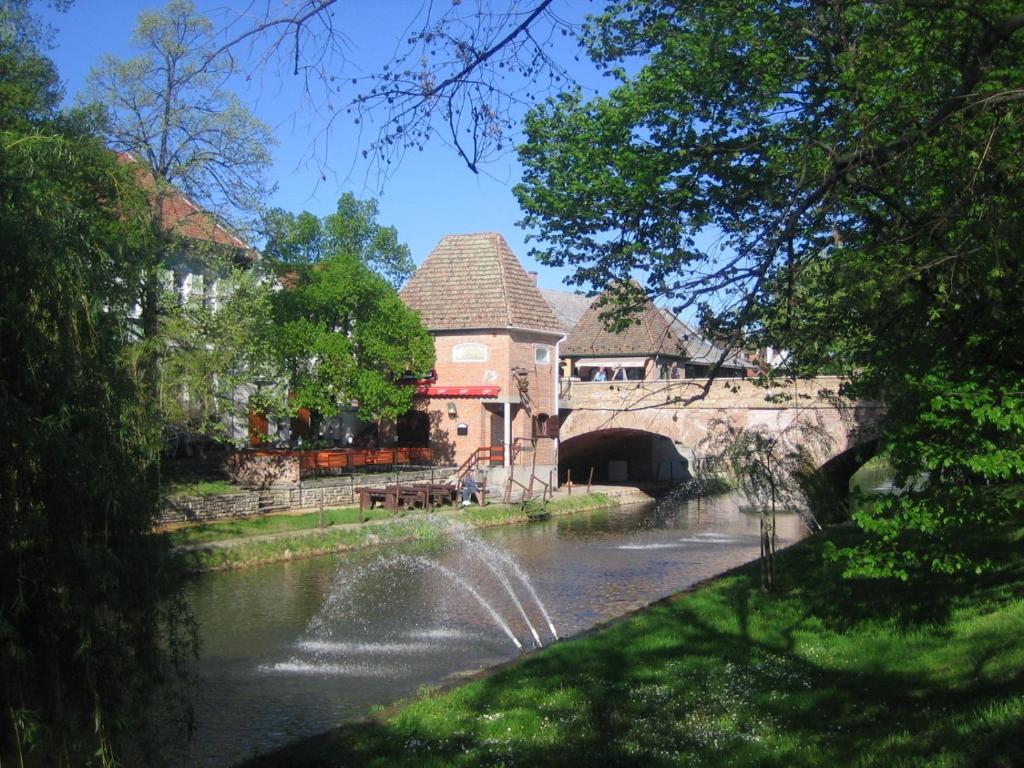 a stone building with a bridge over a river at Árpád-ház Apartmanok in Gyula