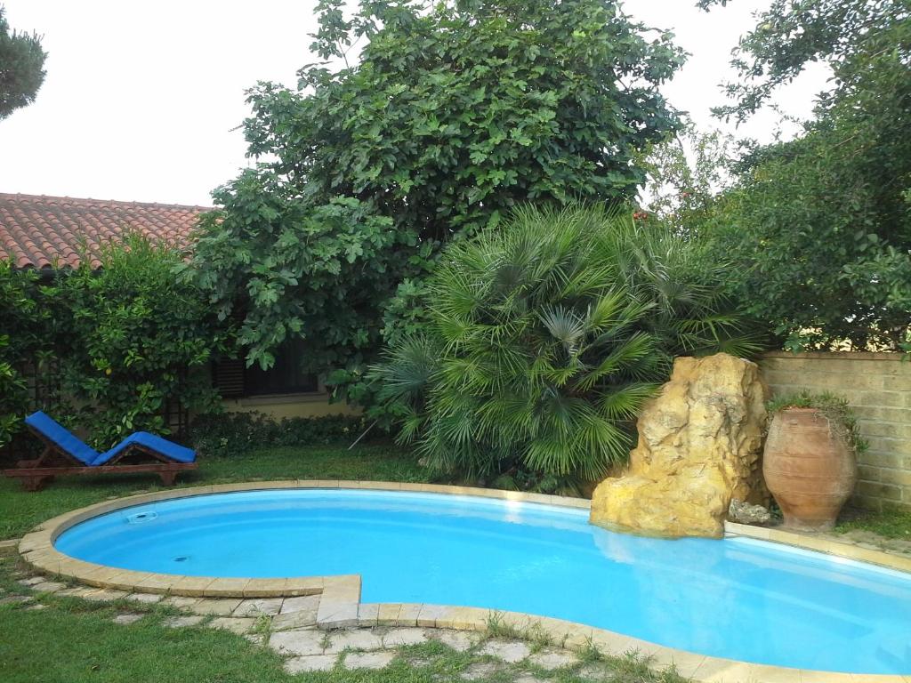 a swimming pool with a rock in a yard at Casa del Sole in Venturina Terme