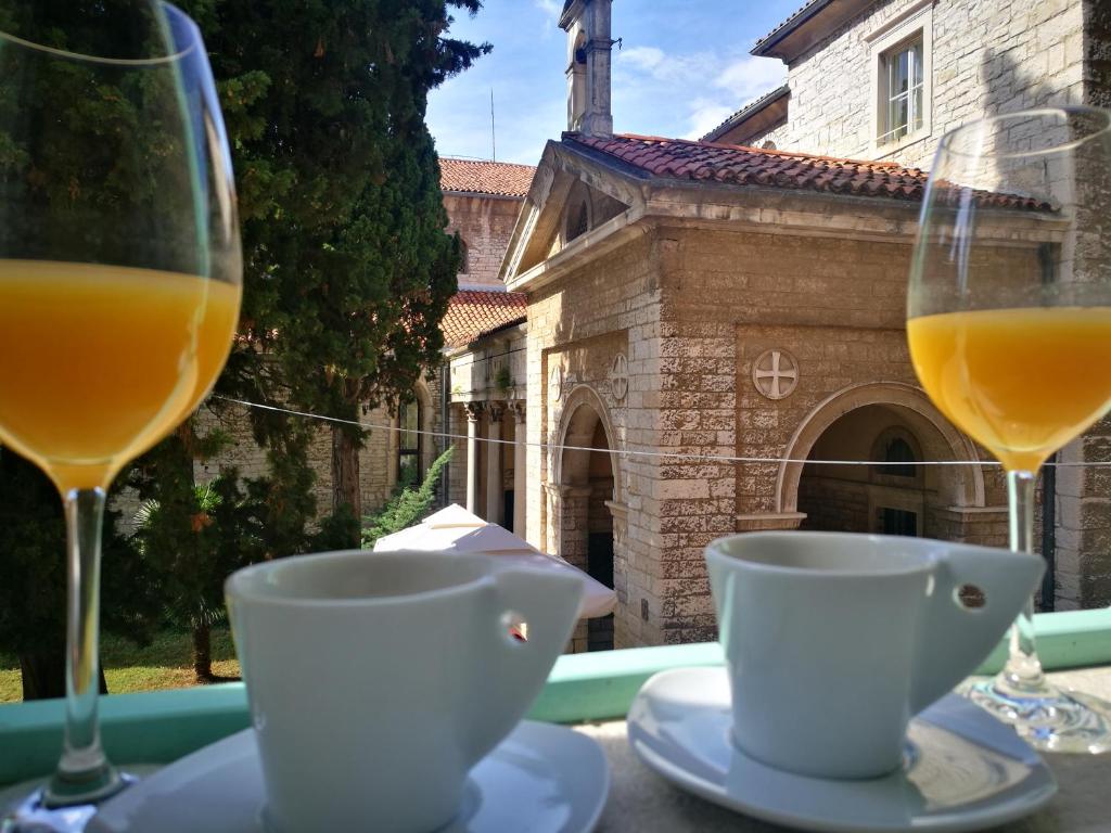 two glasses of orange juice and cups on a table at Candler's old town apartments in Pula