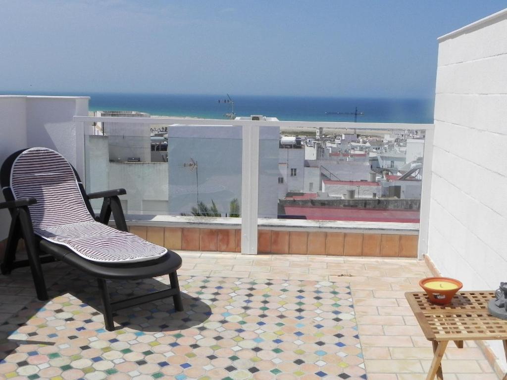 una silla en el balcón con vistas al océano en Apt. Eros en Conil de la Frontera