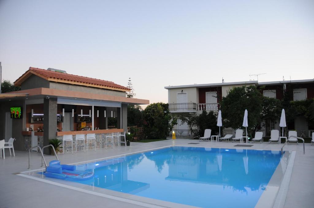 a large blue swimming pool in front of a building at Vicky's Garden in Kalamaki