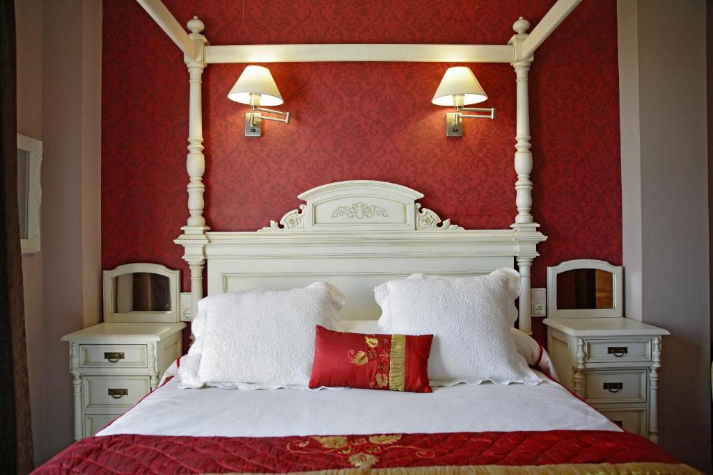 a white bed with two pillows and a red wall at Señorío de Los Bazán in Palacios de la Valduerna