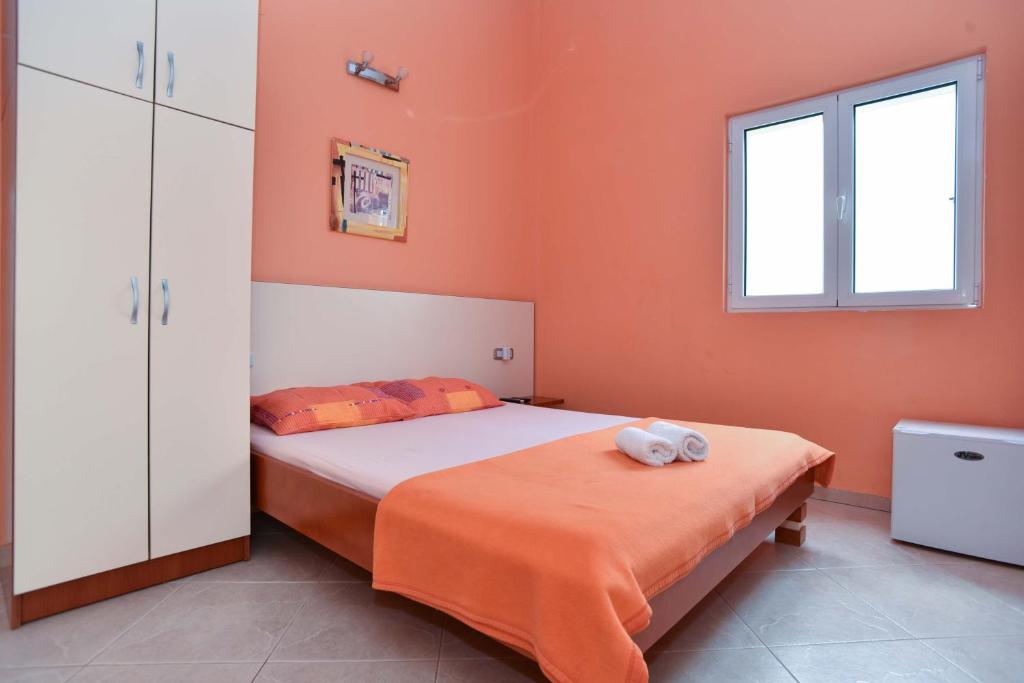 a bedroom with a bed with an orange wall at Vila Hortenzija in Bečići