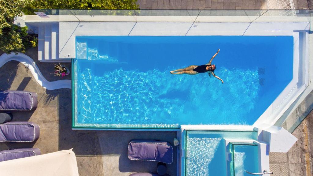un homme nageant dans une piscine d'eau dans l'établissement Micra Anglia Boutique Hotel & Spa, à Andros