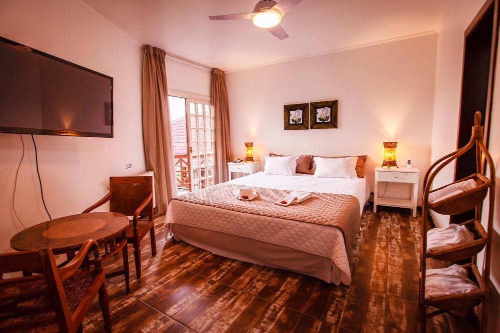 a bedroom with a bed and a table and a tv at Hotel Village da Serra in São Francisco de Paula
