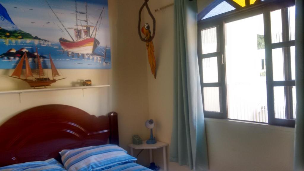 Schlafzimmer mit einem Bett und einem Fenster in der Unterkunft Pousada na praia em Florianópolis in Florianópolis