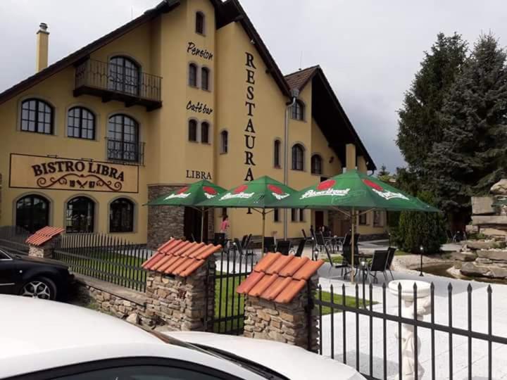 ein Restaurant mit grünen Sonnenschirmen vor einem Gebäude in der Unterkunft Pension Libra in Velešín