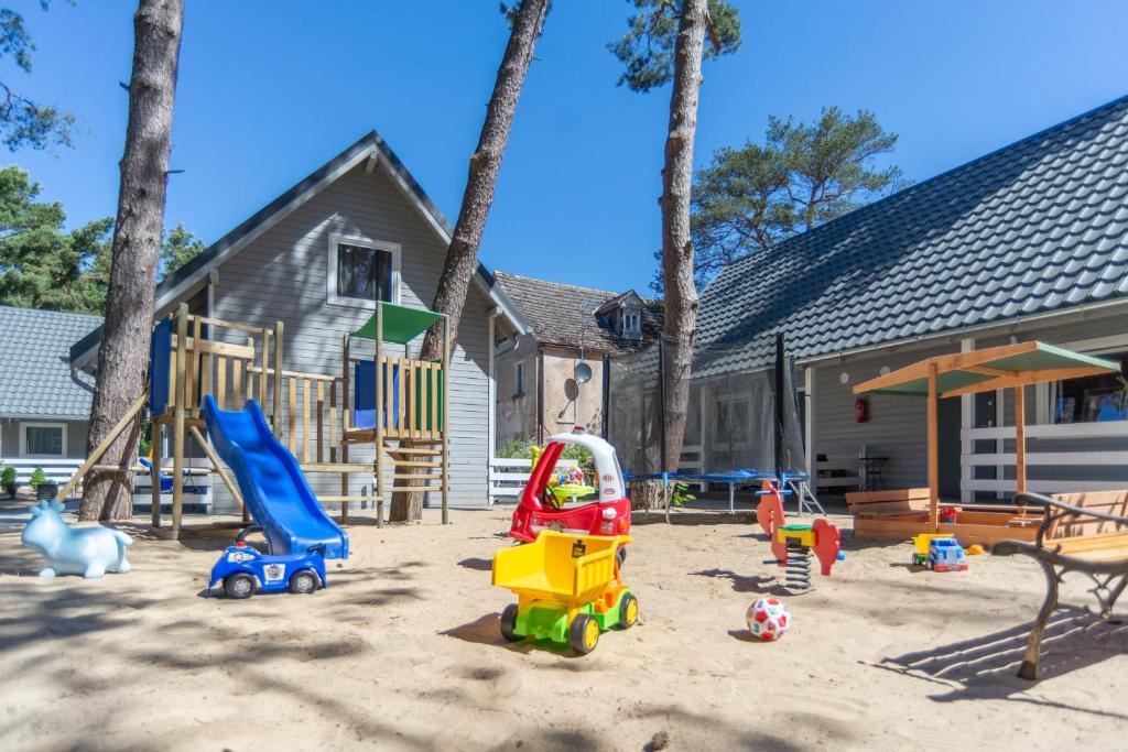 um parque infantil com brinquedos na areia em frente a uma casa em Hubertus Pogorzelica - domki przy plaży em Pogorzelica