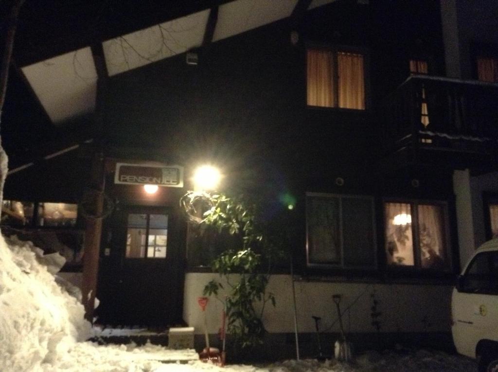 uma casa com uma luz de rua na neve à noite em Pension Roku em Hakuba