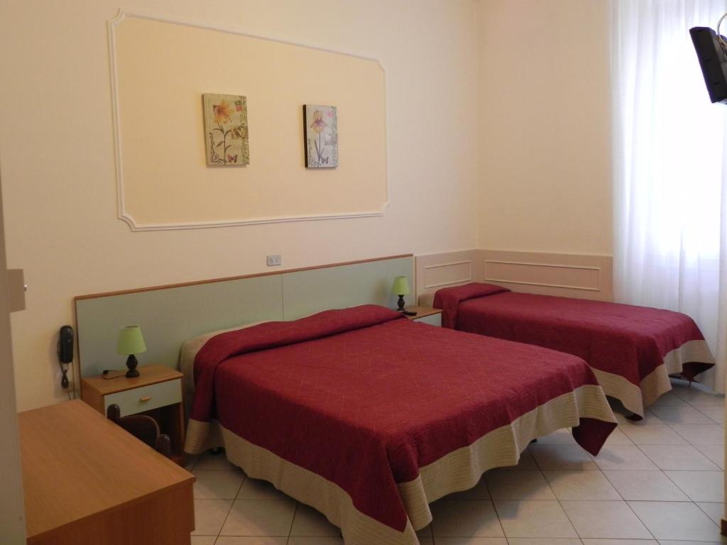 a hotel room with two beds with red covers at Hotel Ondina in Viareggio