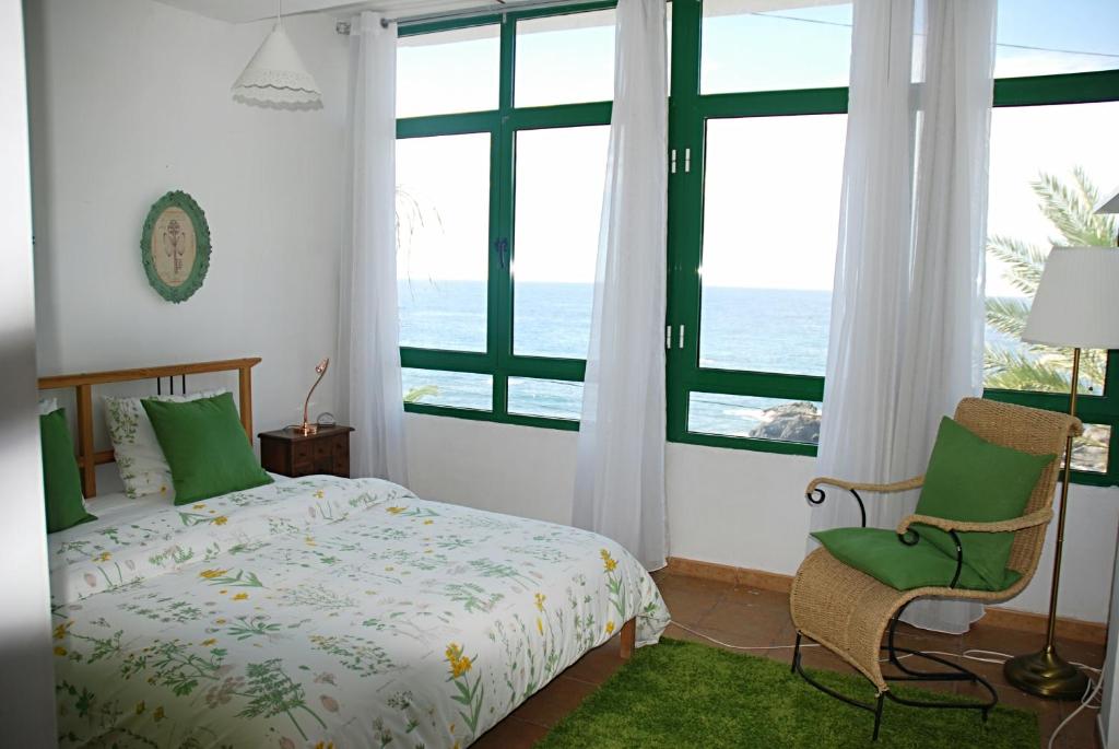 a bedroom with a bed and a chair and the ocean at Ocean Breeze Alcalá in Alcalá
