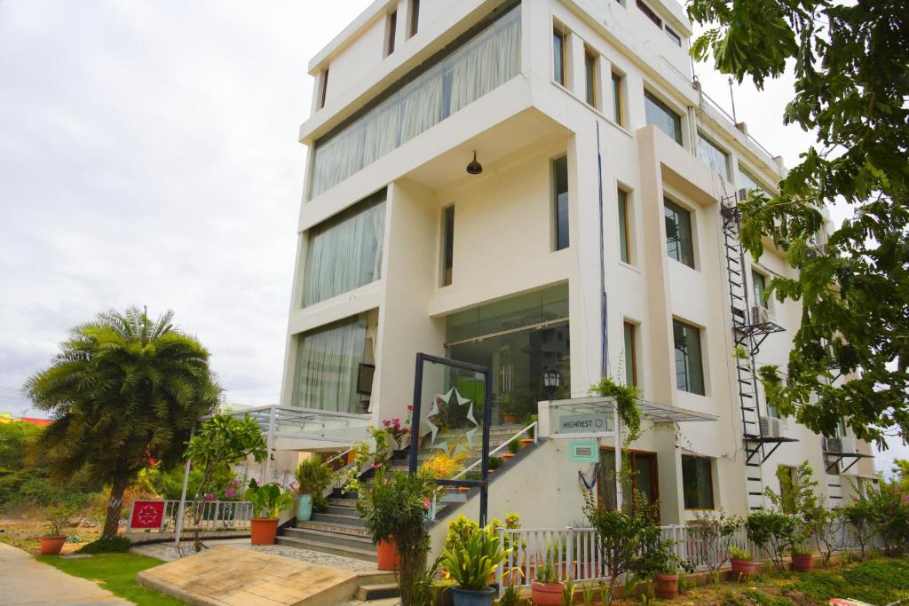 a white building with stairs and plants in front of it at Hotel Highnest in Singapperumālkovil