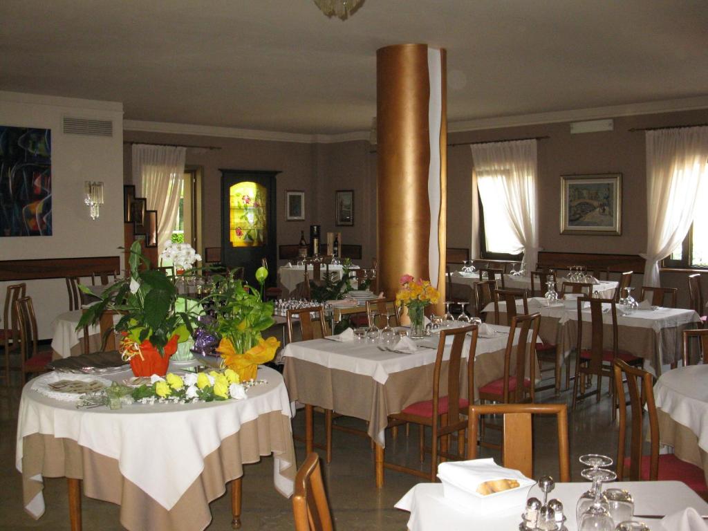 a restaurant with white tables and chairs with flowers on them at Albergo Ristorante Papa in Peschiera del Garda