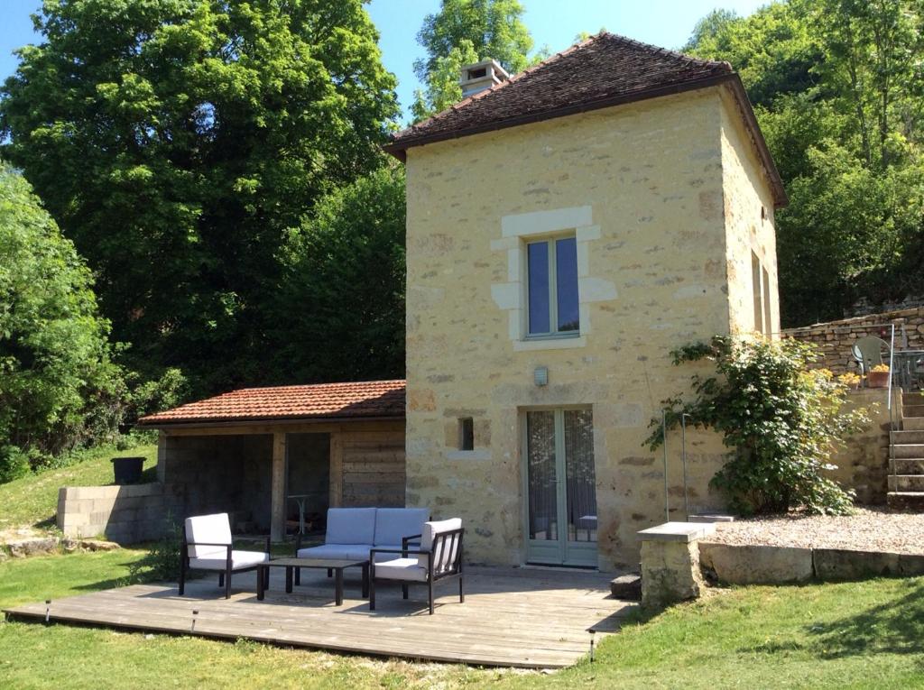 ein Steinhaus mit einem Tisch und Stühlen auf einer Terrasse in der Unterkunft Les Tanneries in Flavigny-sur-Ozerain