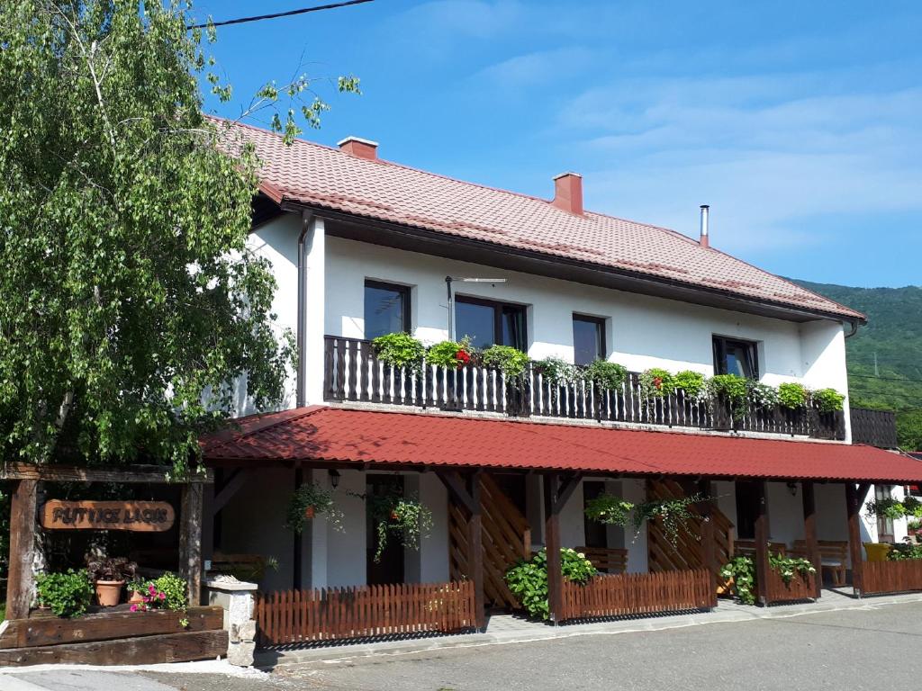 a white building with a balcony with plants on it at Studio Apartments Plitvice Lacus in Korenica