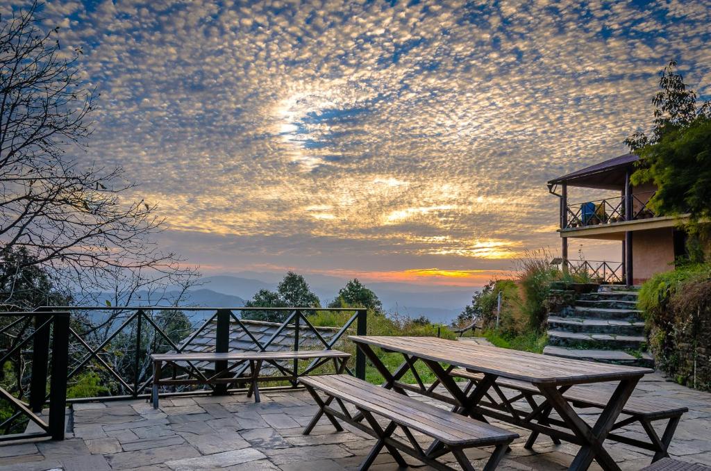 due tavoli da picnic su un patio con tramonto di Binsar Forest Retreat a Binsar