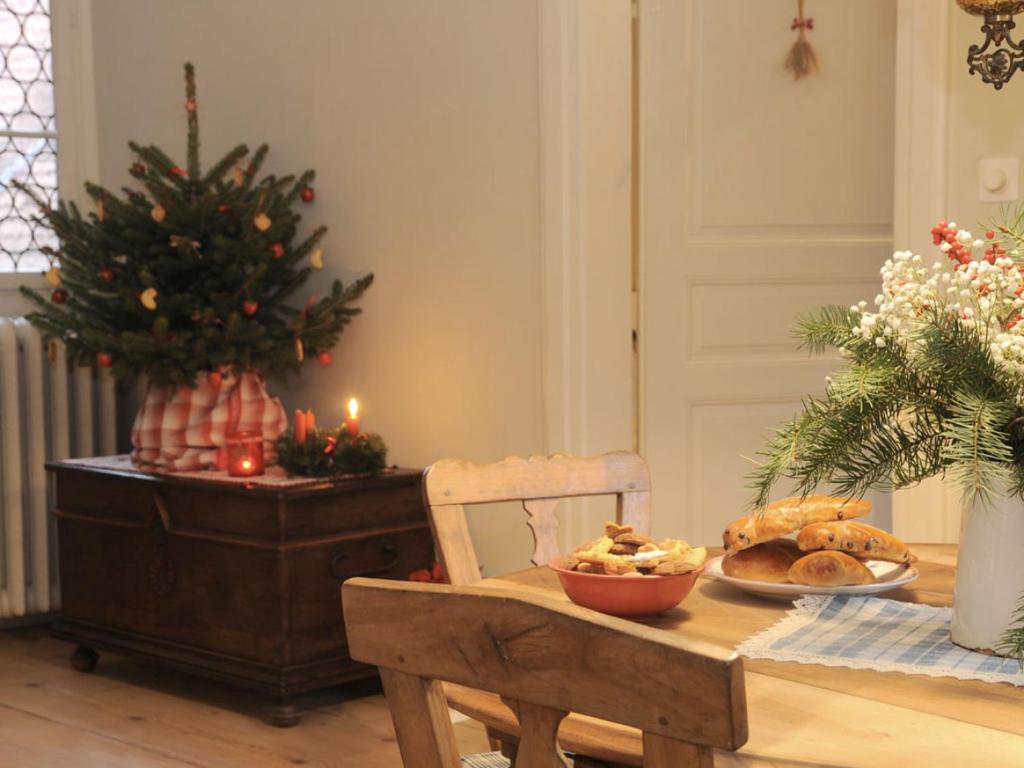 a table with a bowl of bread and a christmas tree at La Maison 1603 in Hunawihr