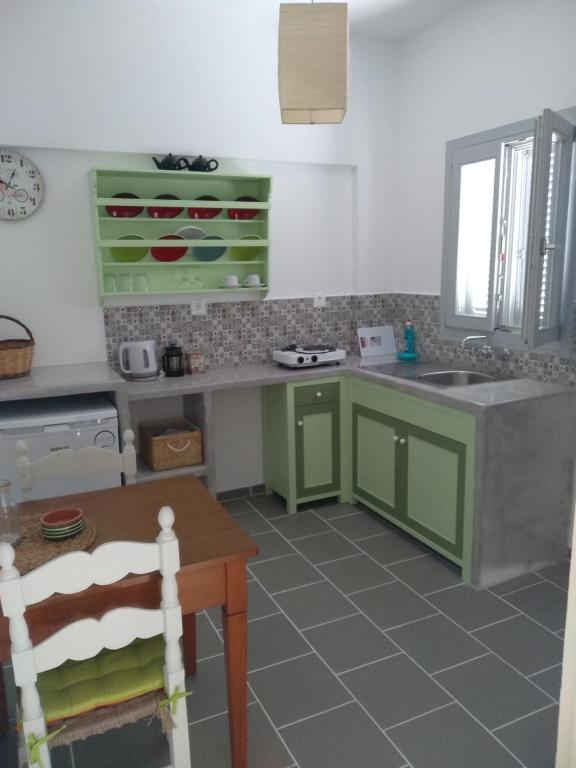 cocina con armarios verdes, fregadero y mesa en Aeolos Apartments, en Kamarai