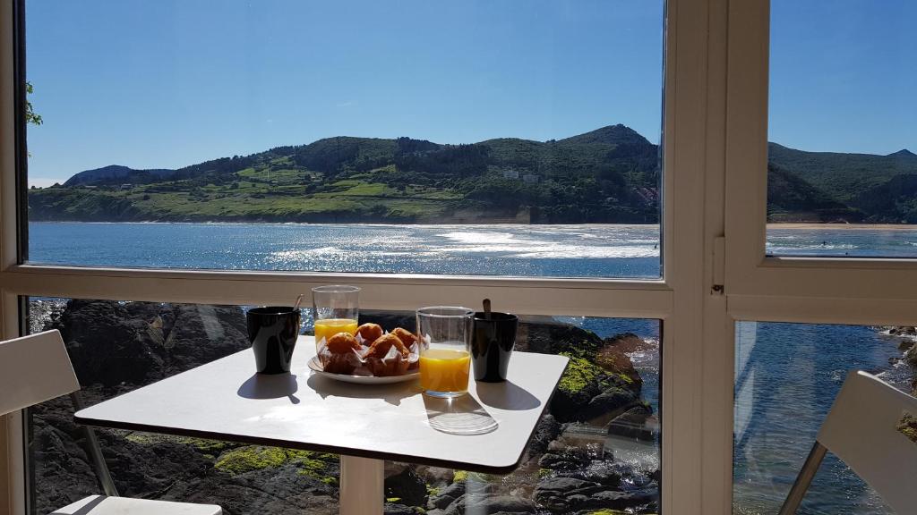 einen Tisch mit einem Teller Essen und Meerblick in der Unterkunft Mundaka Sea Apartment in Mundaka