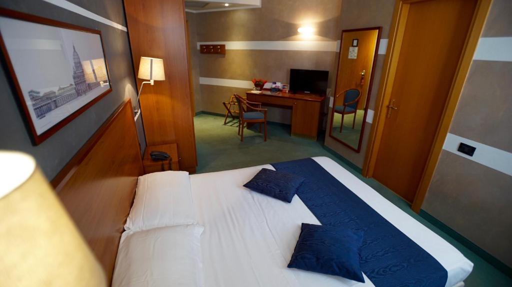 Schlafzimmer mit einem Bett mit blauen Kissen und einem Schreibtisch in der Unterkunft Classic Hotel Tulipano in Terni