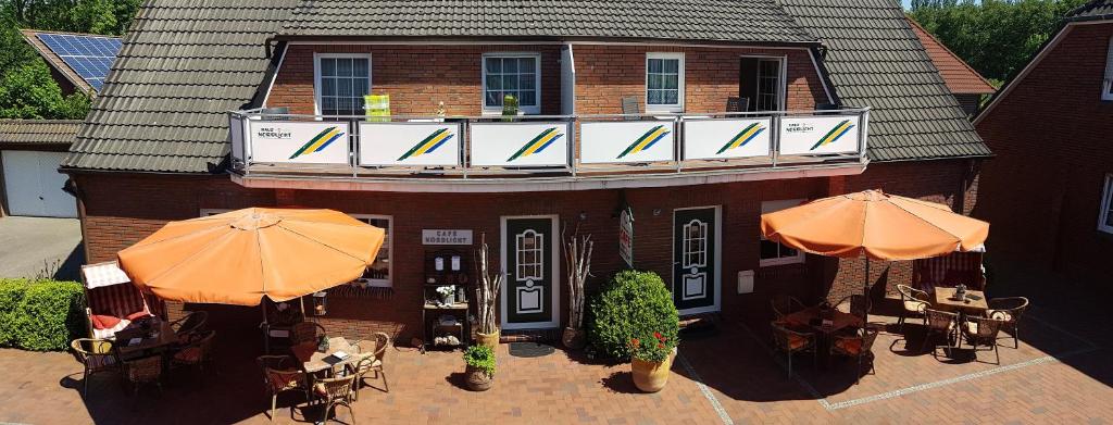 an outdoor patio with tables and umbrellas and a building at Café Hausnordlicht - Ferienwohnung 2 in Dornum