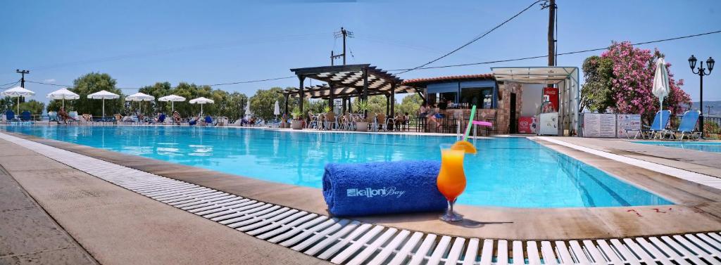 a hotel swimming pool with a drink on the side at Kalloni Bay in Skala Kallonis