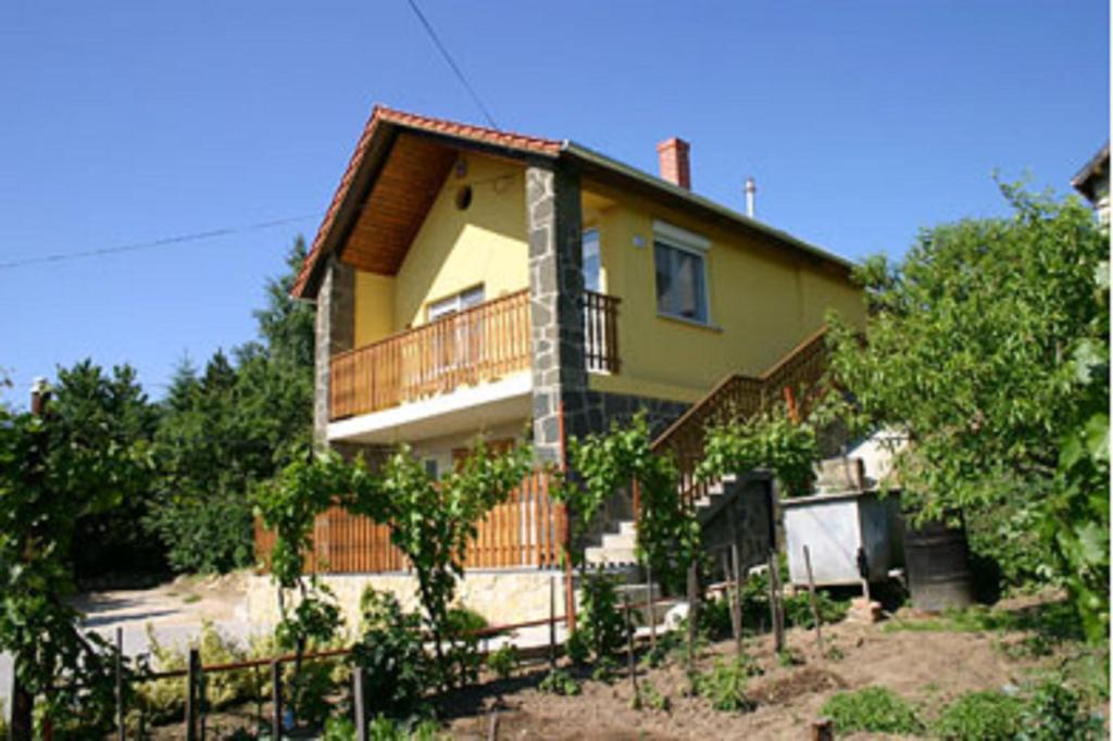 a yellow house with a balcony and trees at Panoráma Apartmanház in Sárvár