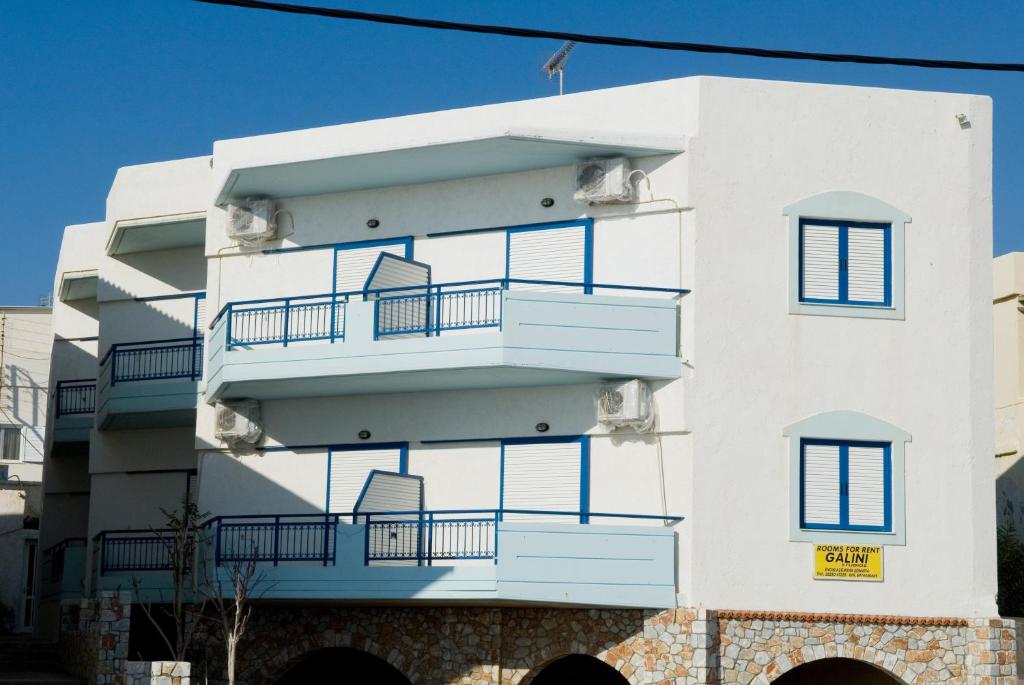 ein weißes Gebäude mit blauen Balkonen darauf in der Unterkunft Galini Studios in Palaiochóra