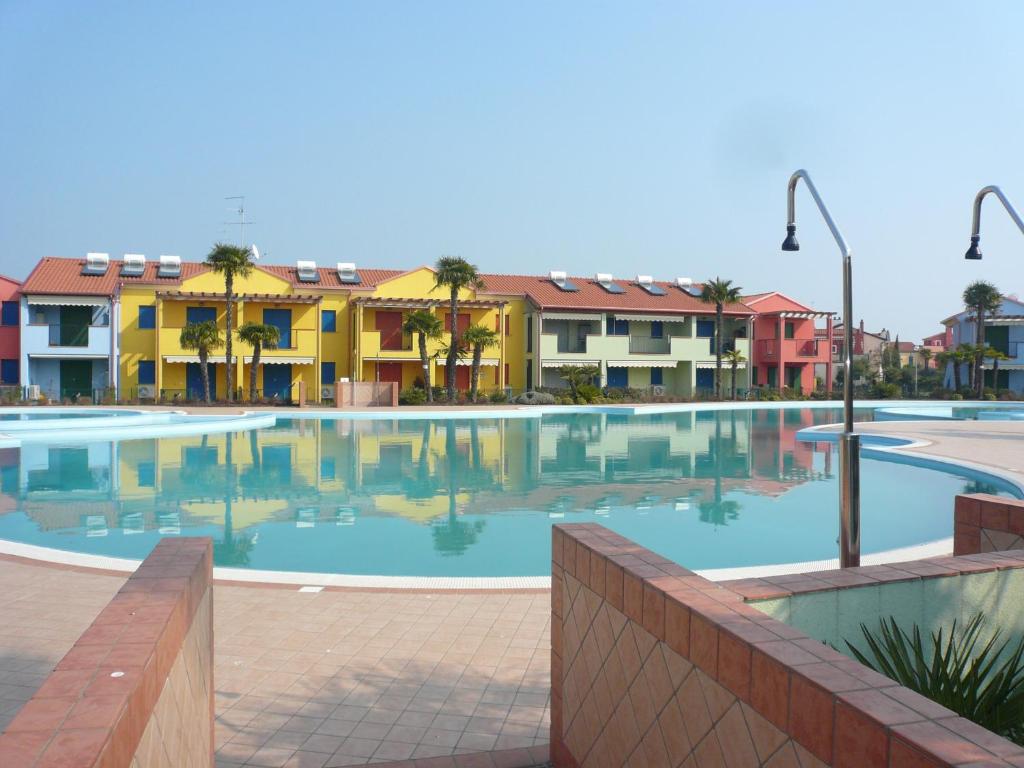 une grande piscine avec des bâtiments en arrière-plan dans l'établissement Porto Antico Village, à Aprilia Marittima