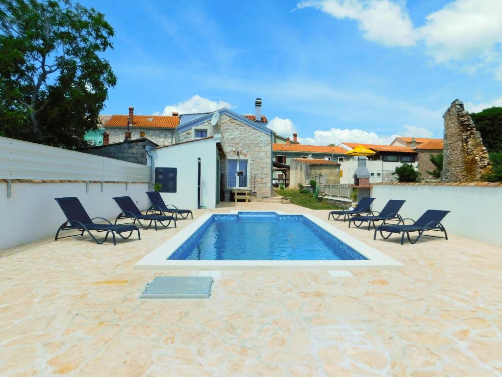 a swimming pool in a yard with chairs and a house at Villa Pax in Marčana