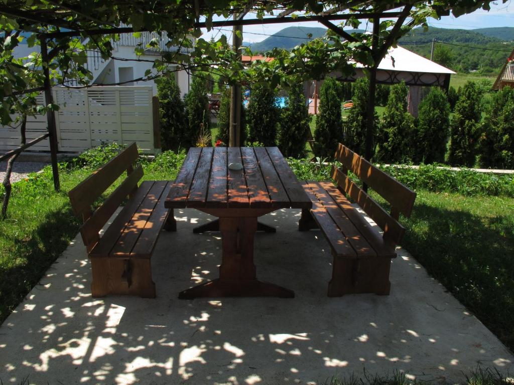 une table de pique-nique et deux bancs assis sous un parasol dans l'établissement Guesthouse Rupčič, à Grabovac