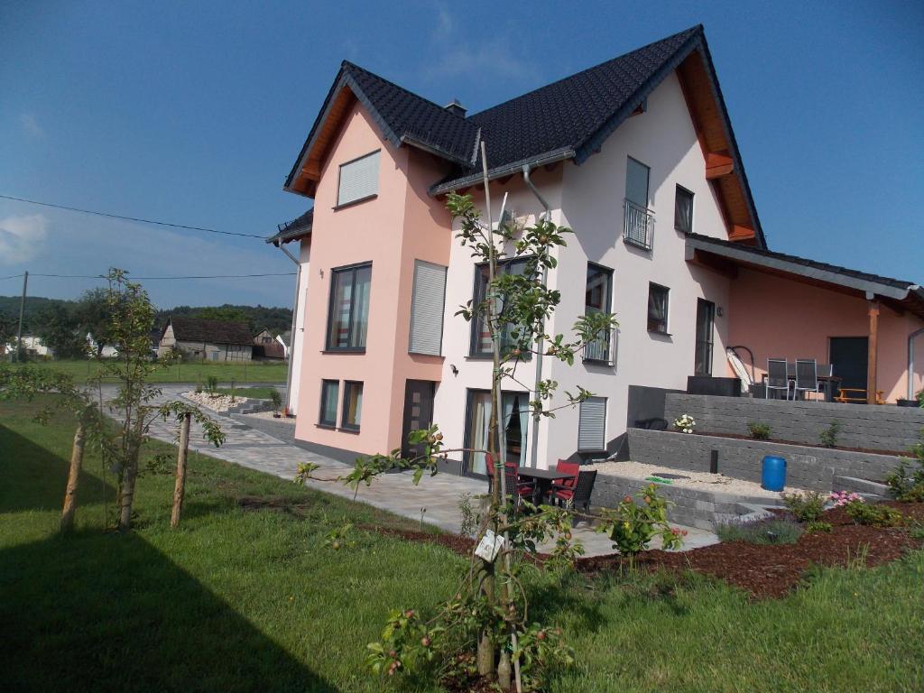 a pink and white house with a tree in the yard at Ferienwohnung Sarah & Thorsten Blum in Kelberg