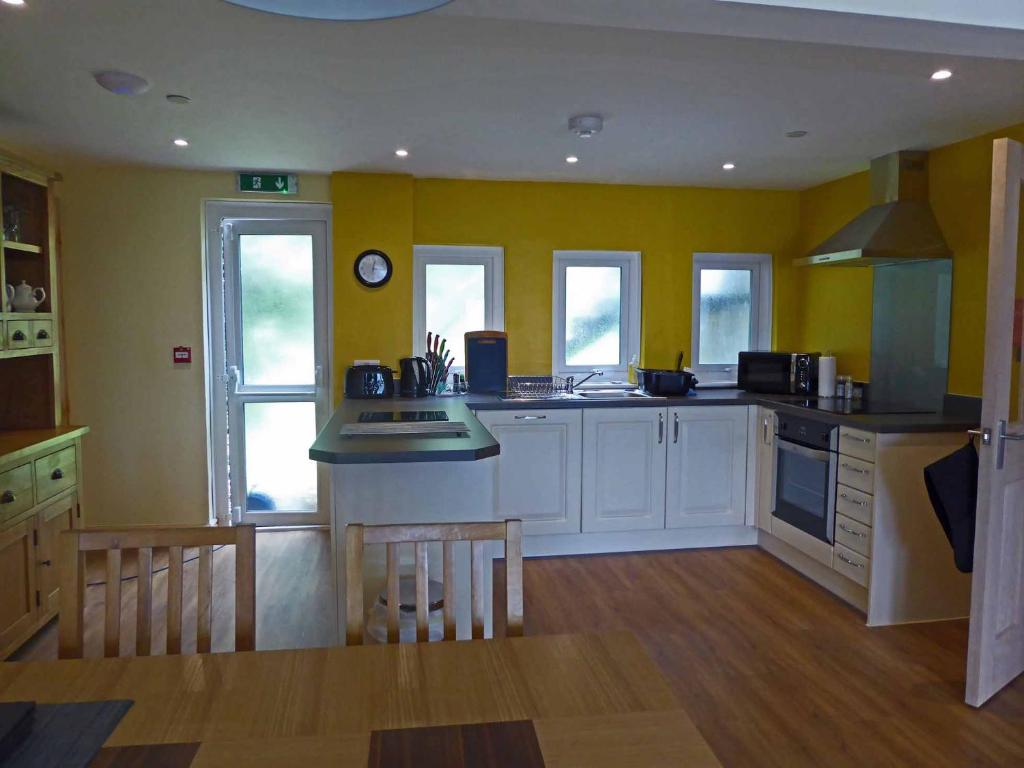 a kitchen with yellow walls and white cabinets at Bryn Melyn Apartments in Barmouth