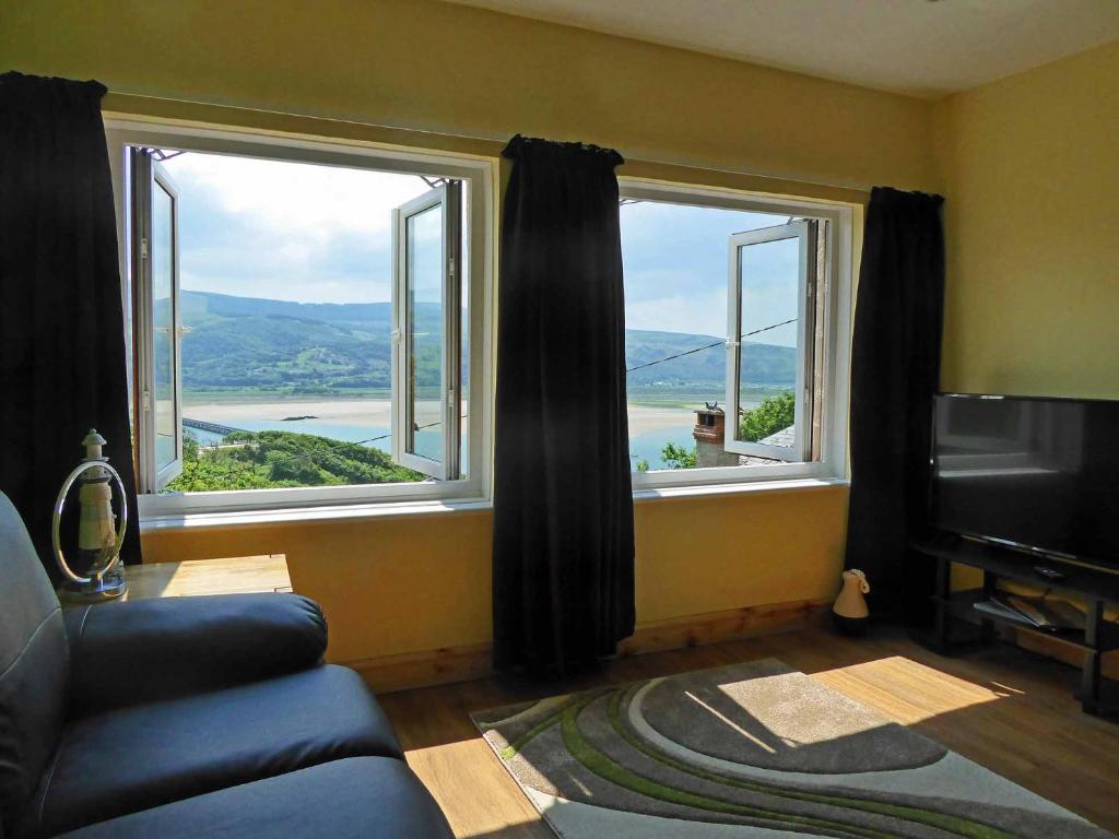 a living room with a couch and two large windows at Bryn Melyn Apartments in Barmouth