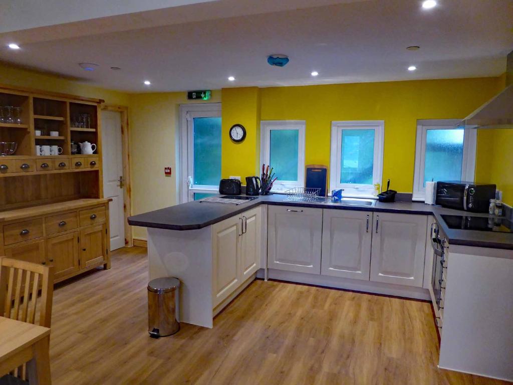 a large kitchen with yellow walls and white cabinets at Bryn Melyn Apartments in Barmouth