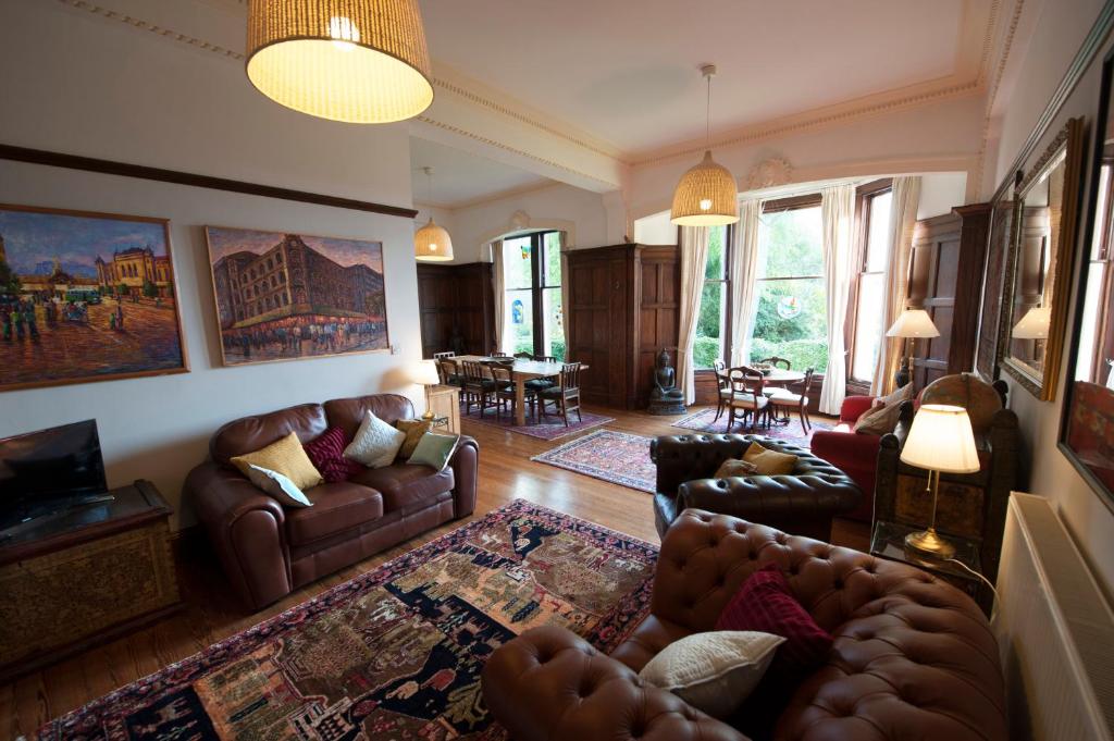 ein Wohnzimmer mit Ledersofas und ein Wohnzimmer mit einem Tisch in der Unterkunft Warriston Apartment at Holm Park in Moffat