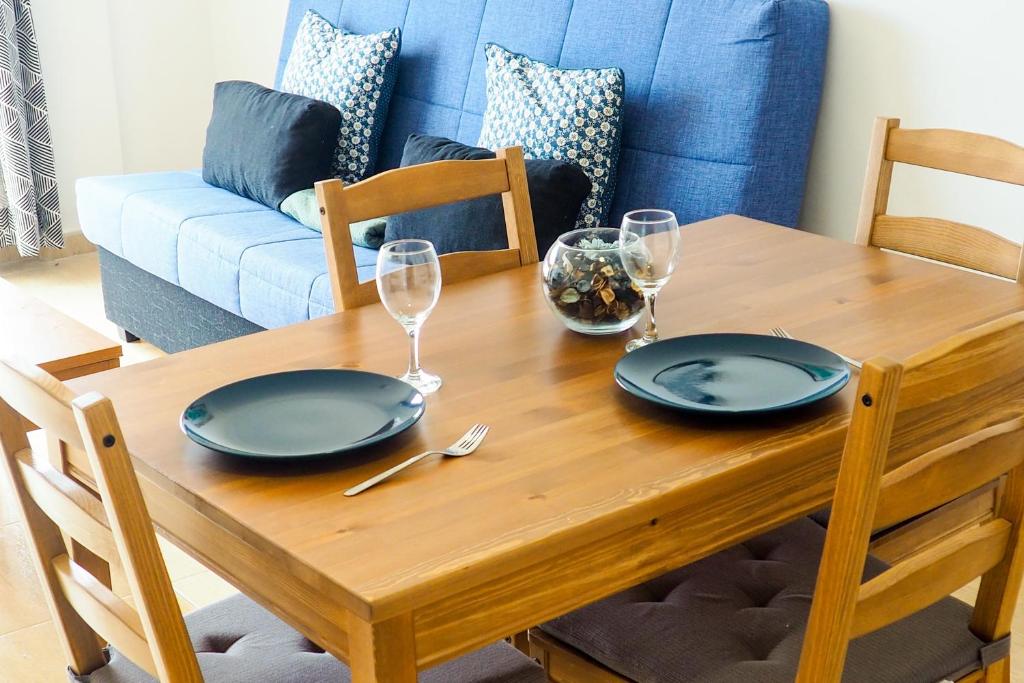 una mesa de madera con dos platos y copas de vino en Buena Vida, en Breña Baja
