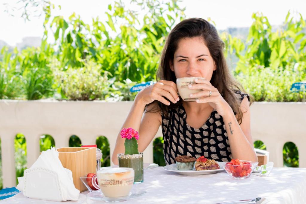 una mujer sentada en una mesa bebiendo una taza de café en B&B Il Giardino Stellato, en Vieste